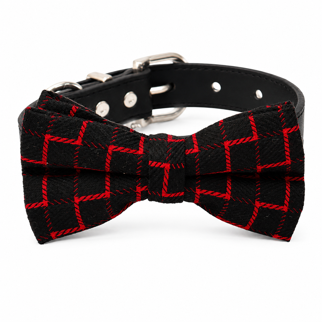 Black and red plaid dog bow tie attached to a black vegan leather dog collar with silver hardware displayed on a white background