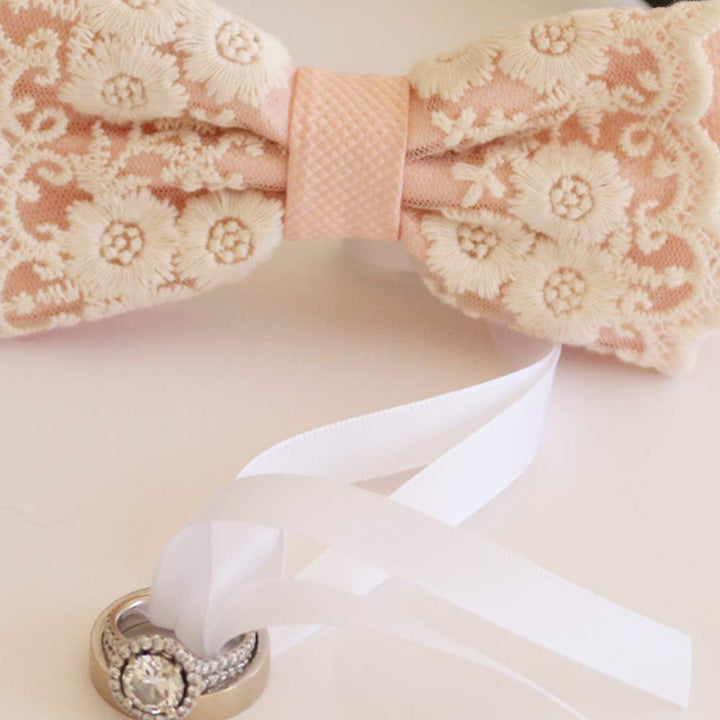 Close-up of blush pink lace ring bearer dog bow tie showing attached wedding ring holder ribbon and decorative ring detail