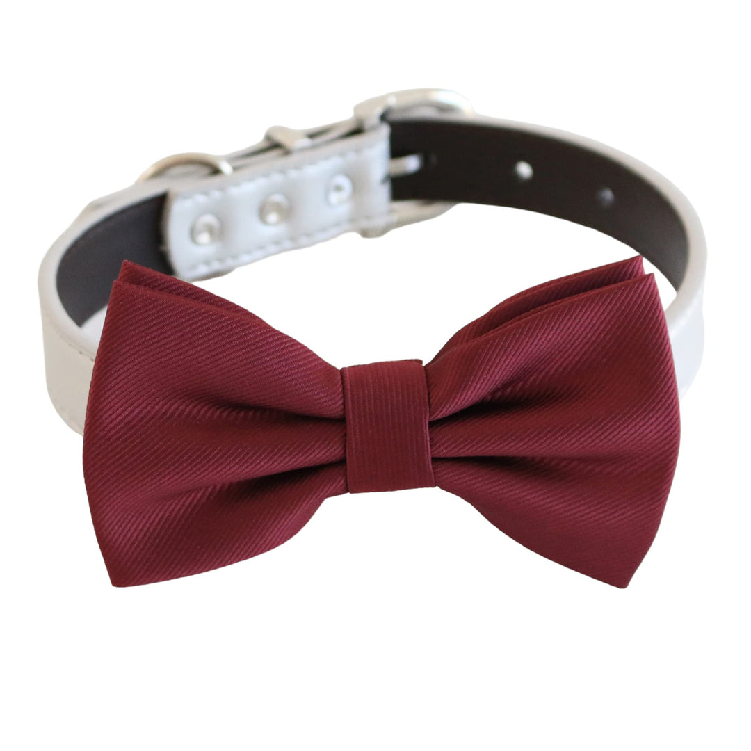 Burgundy ribbed dog bow tie attached to a white vegan leather collar with silver-tone hardware and adjustable fit