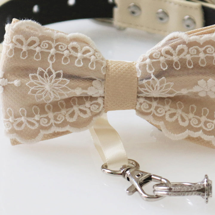 Close-up detail of champagne lace ring bearer dog bow tie featuring embroidered floral lace pattern, attached wedding ring holder ribbon, and decorative ring charm