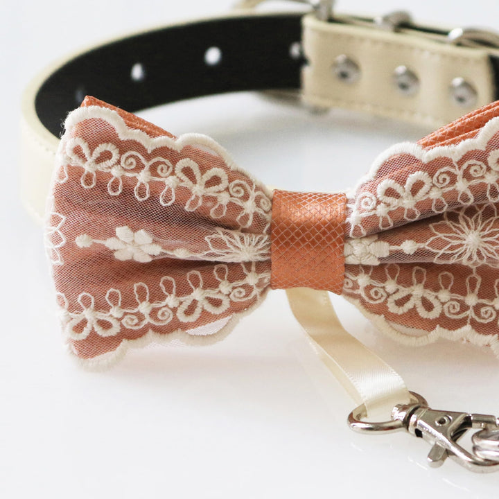 Close-up detail of copper lace ring bearer dog bow tie with embroidered floral lace overlay, attached wedding ring holder ribbon, decorative ring charm, and adjustable vegan leather collar