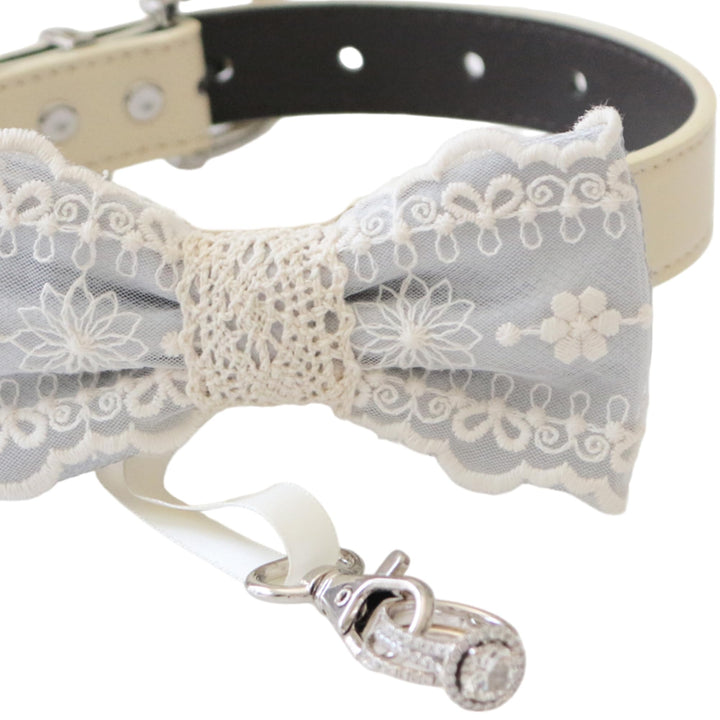 Close-up detail of gray lace ring bearer dog bow tie featuring embroidered floral lace pattern, attached wedding ring holder ribbon, and decorative ring charm