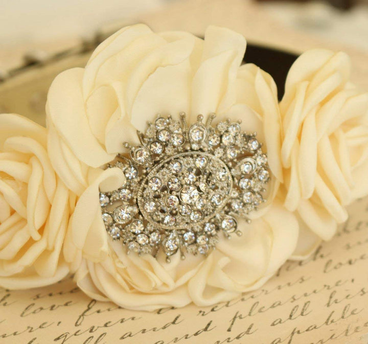 Close-up of ivory floral dog collar featuring an ornate crystal medallion centerpiece and handcrafted rose flowers.