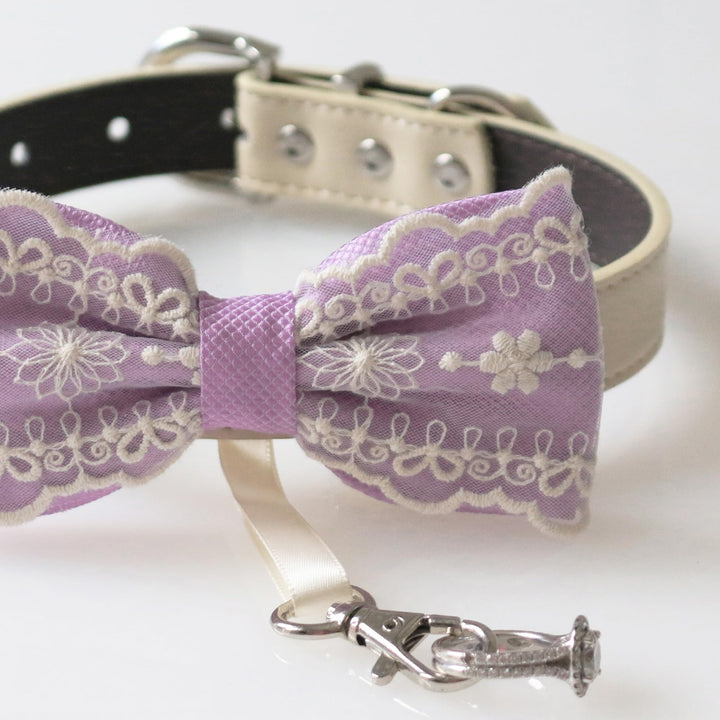Close-up detail of lilac lace ring bearer dog bow tie featuring embroidered floral lace pattern, attached wedding ring holder ribbon, and decorative ring charm
