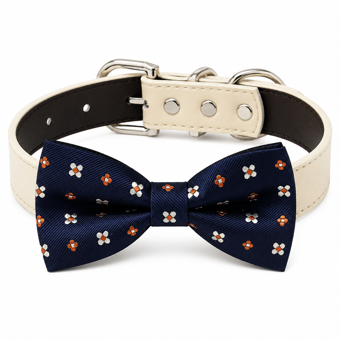 Navy blue dog bow tie collar with orange and white floral pattern, cream vegan leather collar, and silver-tone hardware