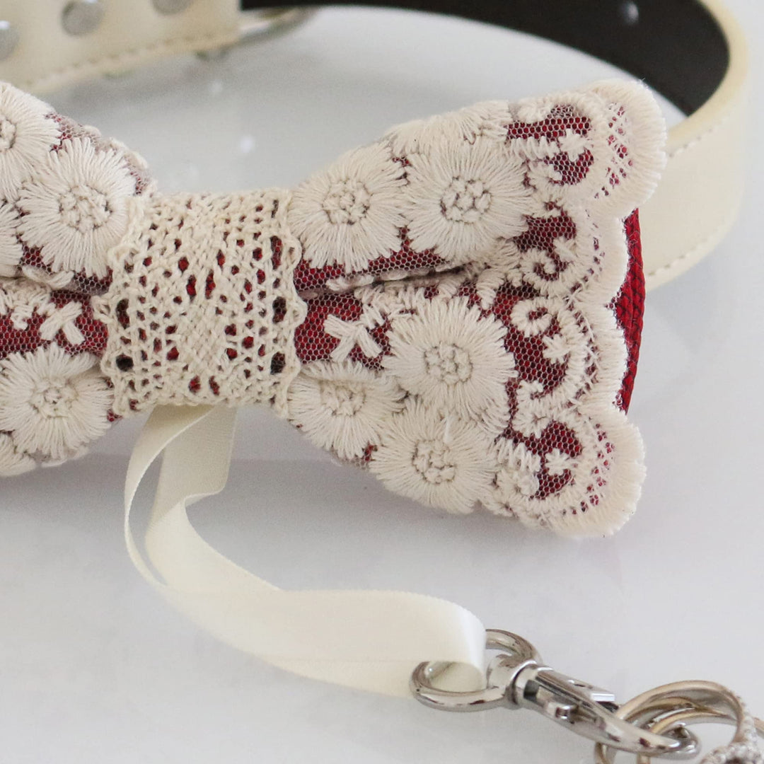 Close-up view of red floral lace ring bearer dog bow tie showing embroidered flower lace details, decorative center band, and attached wedding ring holder ribbon