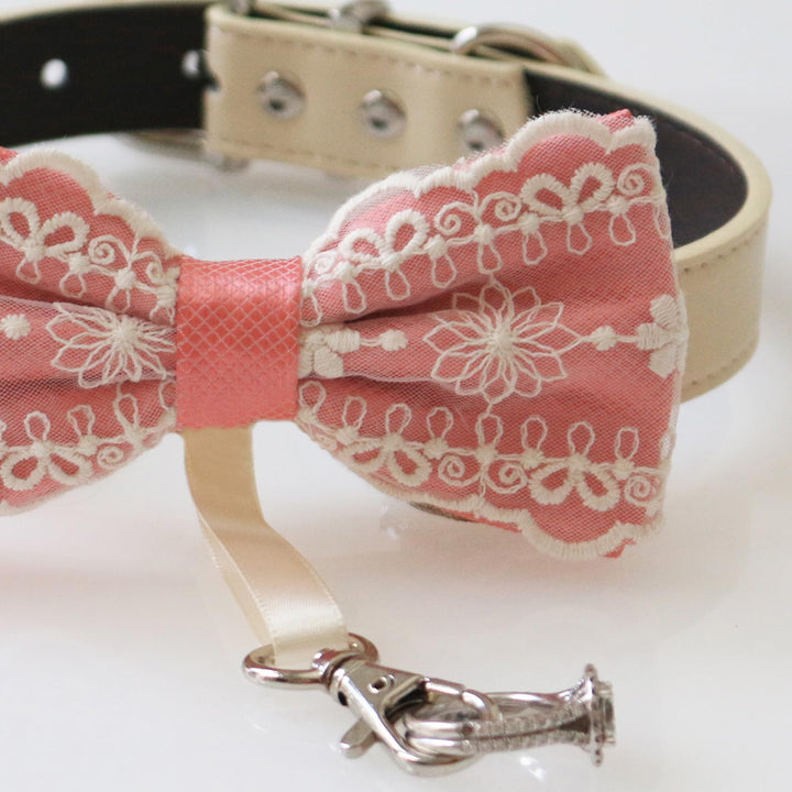 Close-up detail of salmon lace ring bearer dog bow tie with embroidered floral lace pattern, attached wedding ring holder ribbon, decorative ring charm, and adjustable vegan leather collar