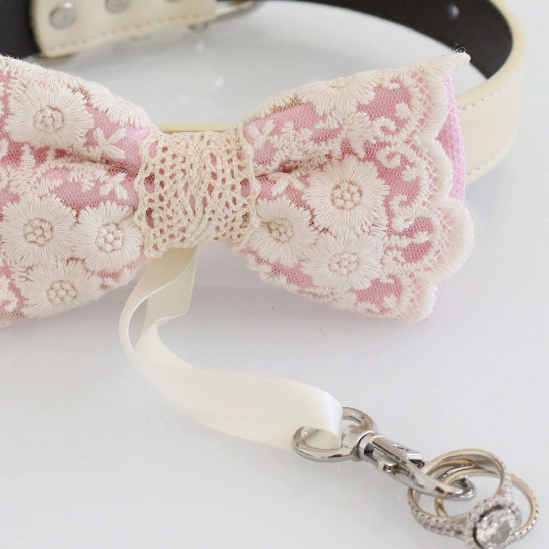 Close-up detail of soft pink lace ring bearer dog bow tie featuring embroidered floral lace pattern, attached wedding ring holder ribbon, and decorative ring charm
