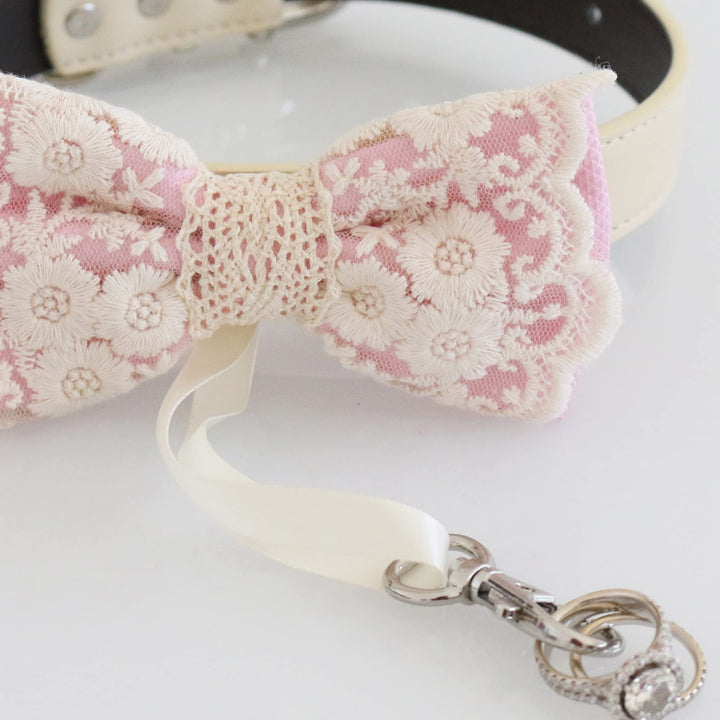 Close-up detail of soft pink lace ring bearer dog bow tie featuring embroidered floral lace pattern, attached wedding ring holder ribbon, and decorative ring charm