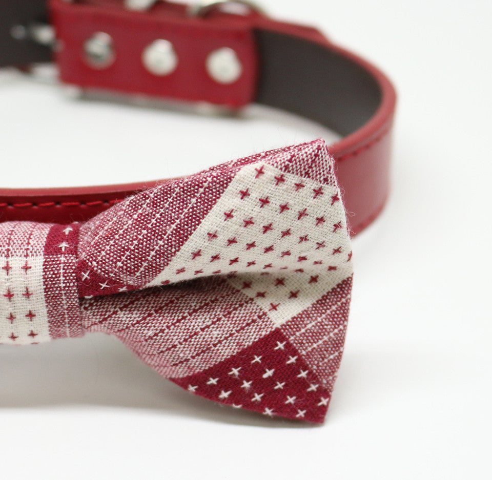 Close-up detail of a burgundy and cream patchwork dog bow tie with stitched cross pattern accents.