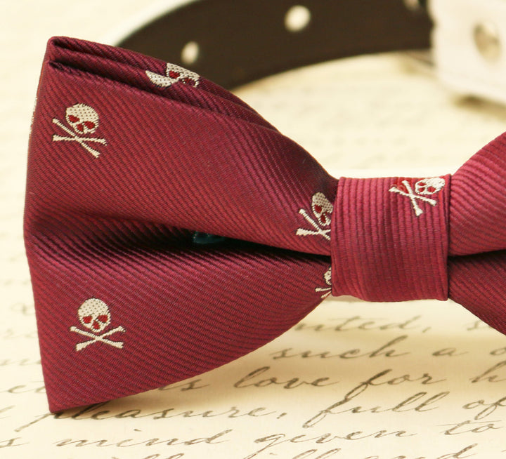 Close-up of burgundy dog bow tie with skull and crossbones pattern