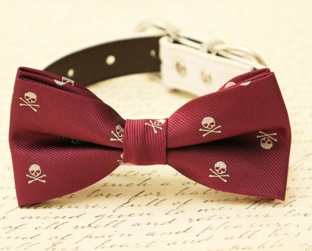 Burgundy skull print dog bow tie attached to a white vegan leather collar on a vintage script background