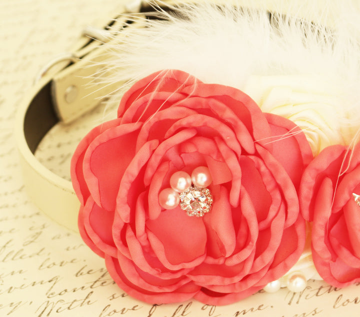 Close-up of coral ring bearer dog collar with handmade flower, pearl and crystal center accents, ivory rosettes, and soft white feather details.