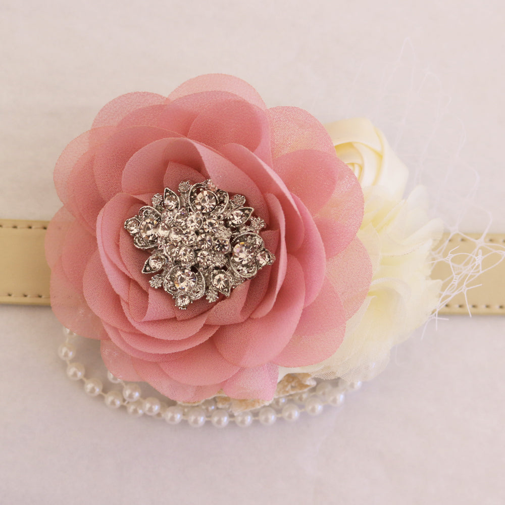 Close-up of coral pink flower dog collar with rhinestone brooch center, ivory floral accents, pearl garland, and decorative veil detail.