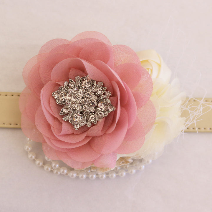 Close-up of coral pink flower dog collar with rhinestone brooch center, ivory floral accents, pearl garland, and decorative veil detail.