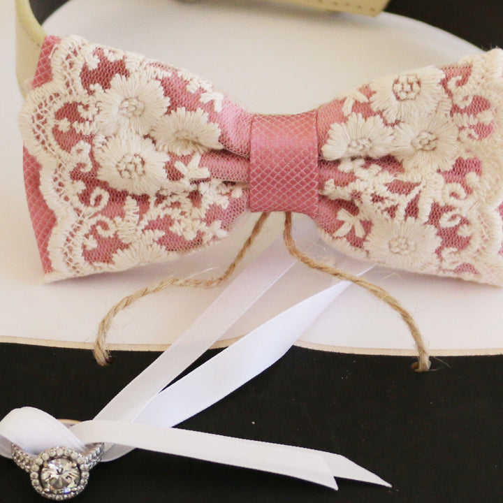 Dusty rose ring bearer dog bow tie close-up featuring floral embroidered lace overlay, blush pink center band, and attached wedding ring holder ribbon
