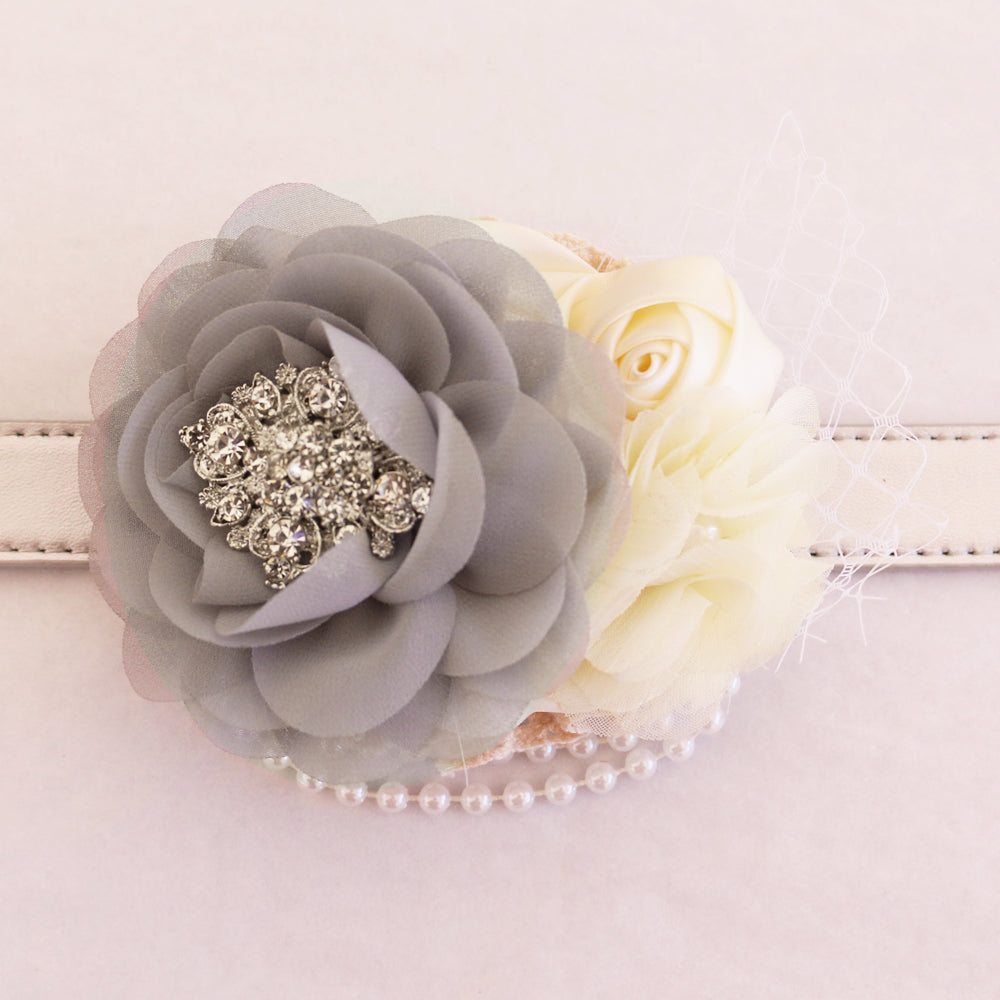 Close-up of gray chiffon flower dog collar with ivory rose accents, pearl strand detail, crystal brooch, and decorative veil.