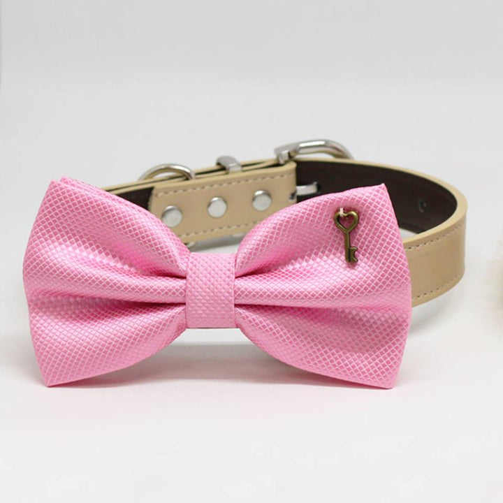 Pink textured dog bow tie collar with vintage key charm attached to a cream vegan leather collar.