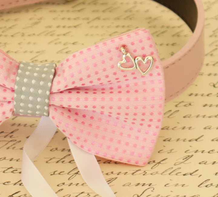 Close-up of a pink polka dot dog bow tie with gray center accent and silver heart charm.