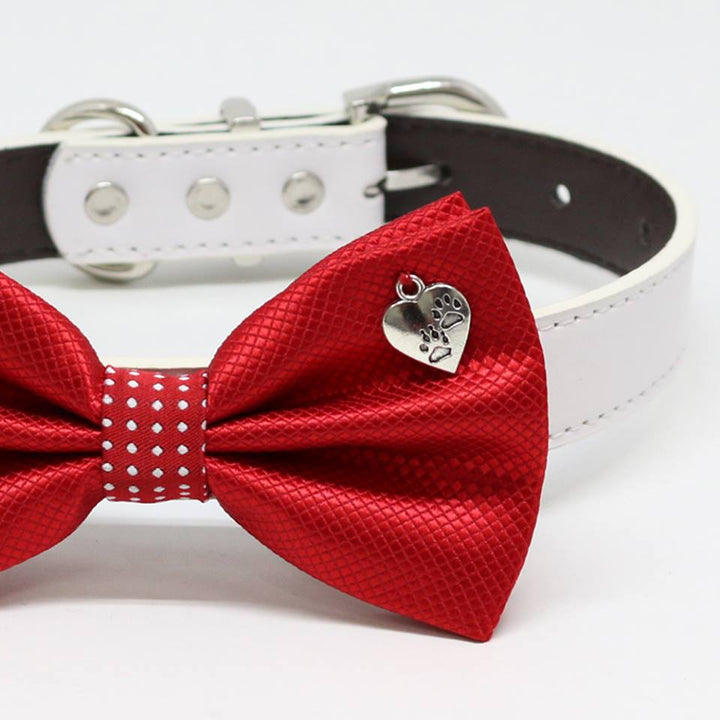 Close-up of red metallic dog bow tie with paw print heart charm detail.