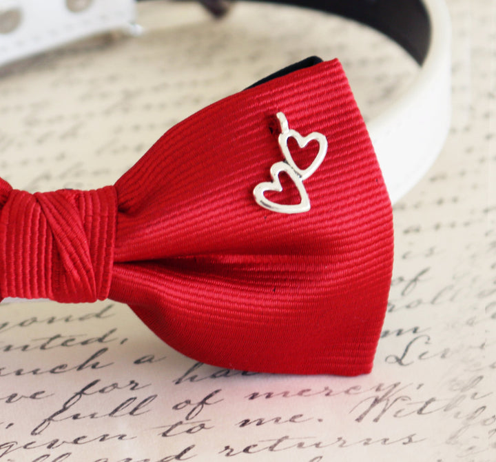 Close-up of red ribbed dog bow tie with silver double heart charm detail.