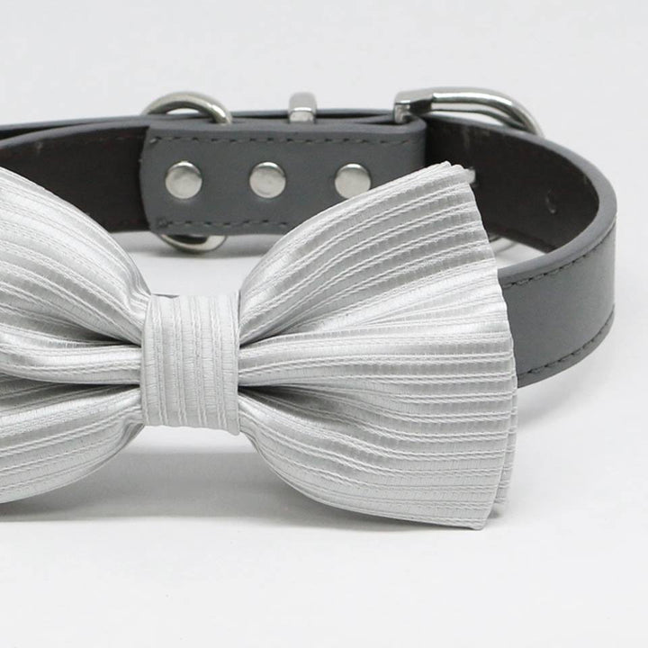 Close-up of a silver striped satin dog bow tie attached to a black vegan leather collar.