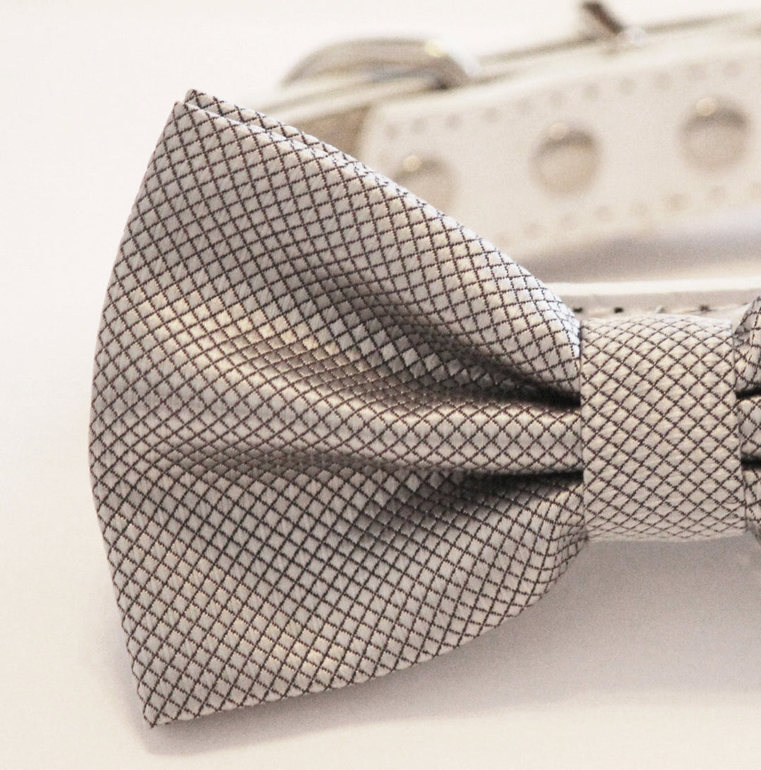 Close-up of a silver textured satin ring bearer dog bow tie with woven diamond pattern.
