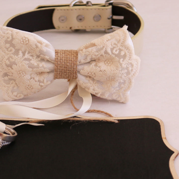 White lace ring bearer dog bow tie collar with attached wedding ring holder ribbon and decorative ring displayed beside a blank chalkboard sign for wedding personalization