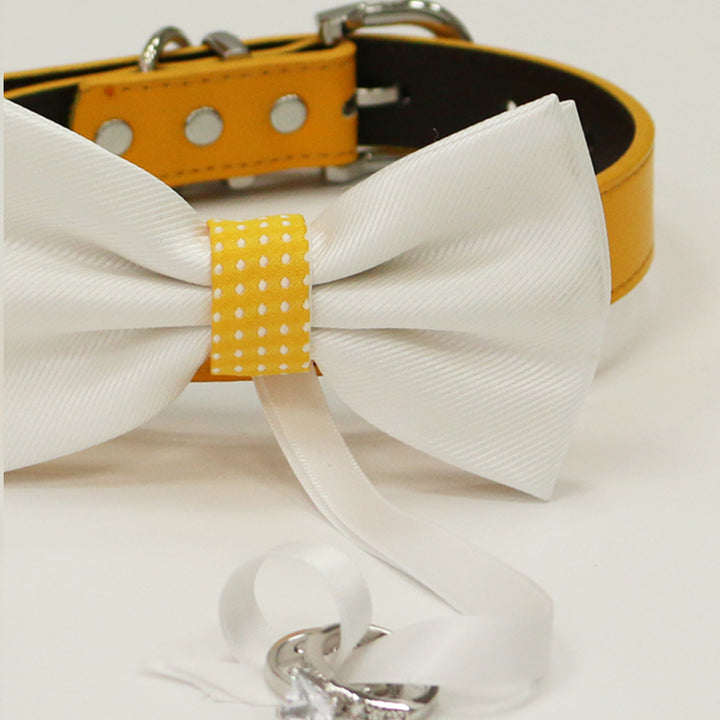Close-up of a white ring bearer dog bow tie with yellow polka dot center accent and wedding ring ribbon.